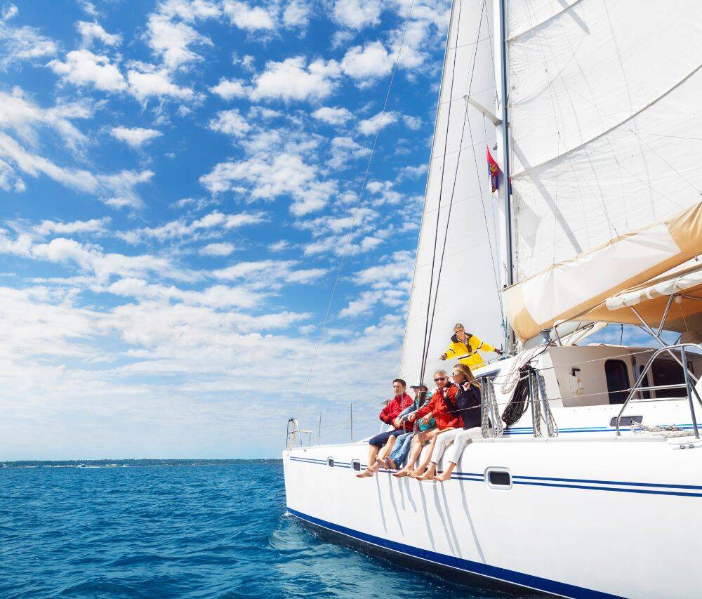 People relaxing on a sailing yacht during a September charter, wearing casual clothing, sunglasses, and hats.